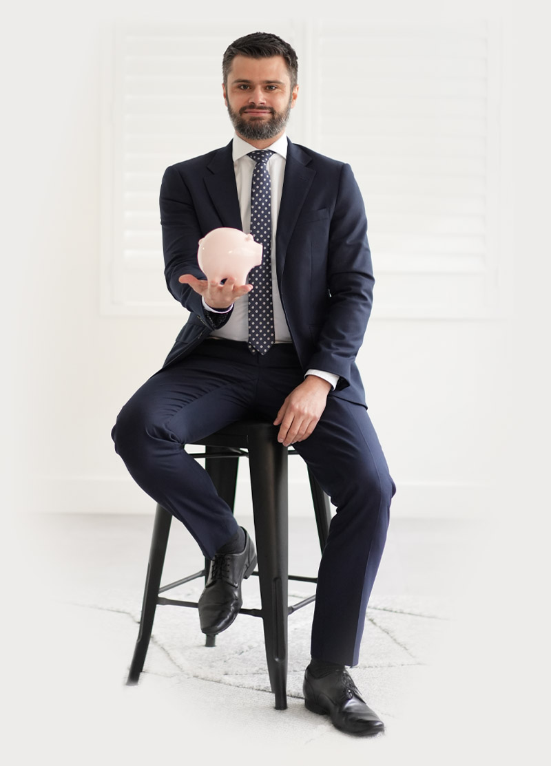 Man in a suit holding a pink piggy bank.